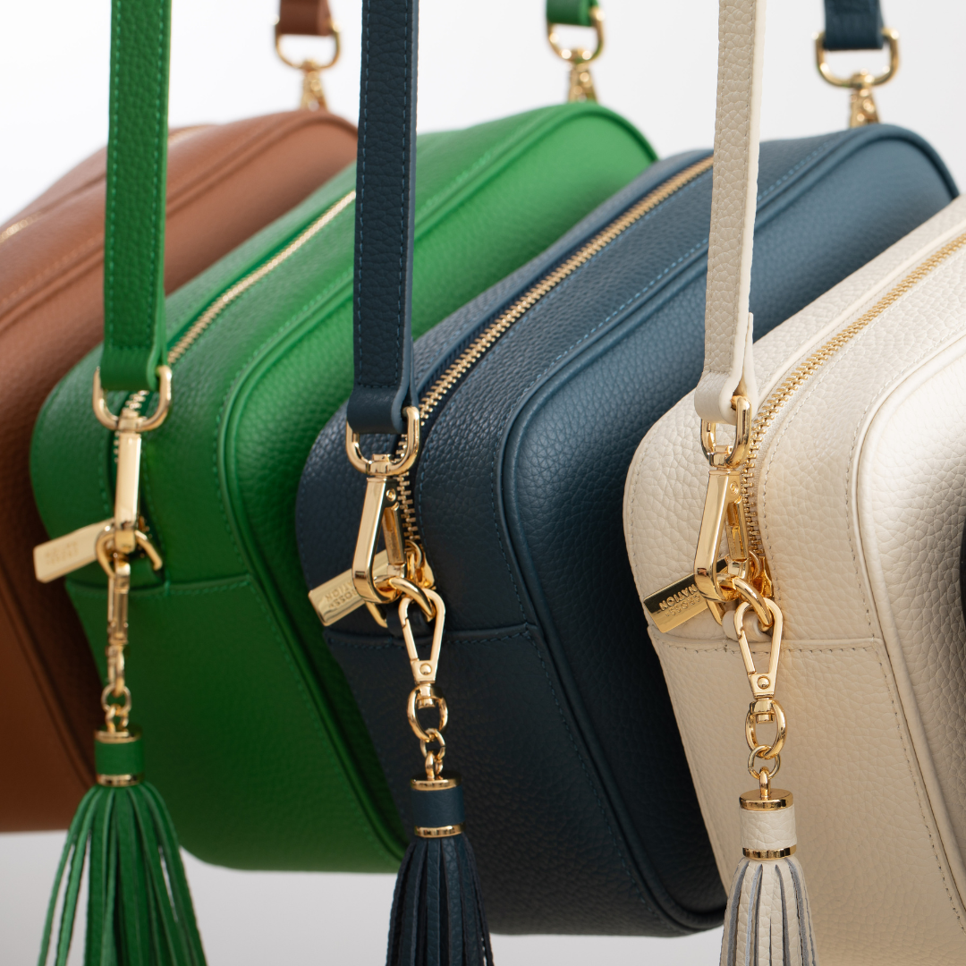 Four handbags in different colors with matching tassel straps.