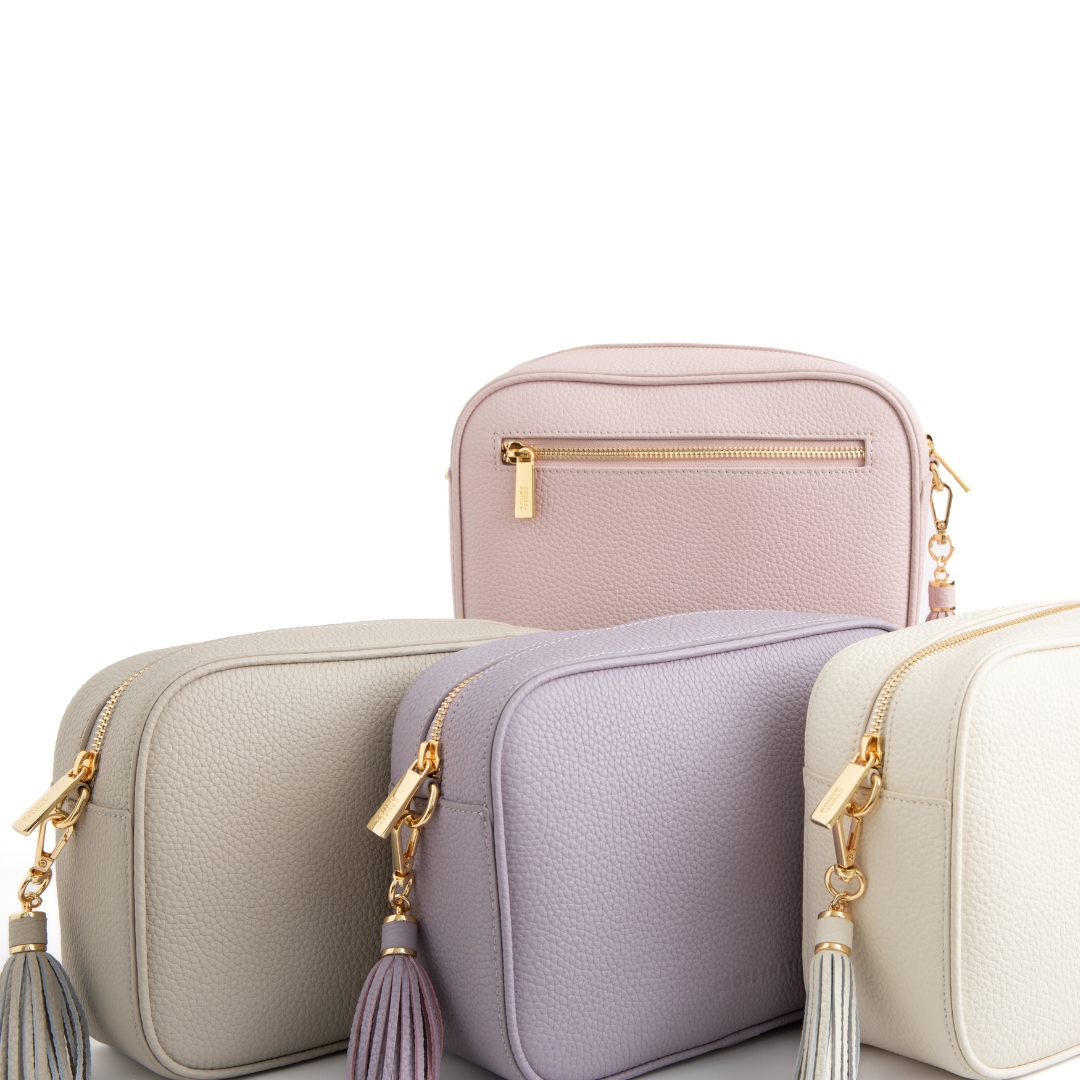 Four small handbags in different colors with gold zippers on a white background