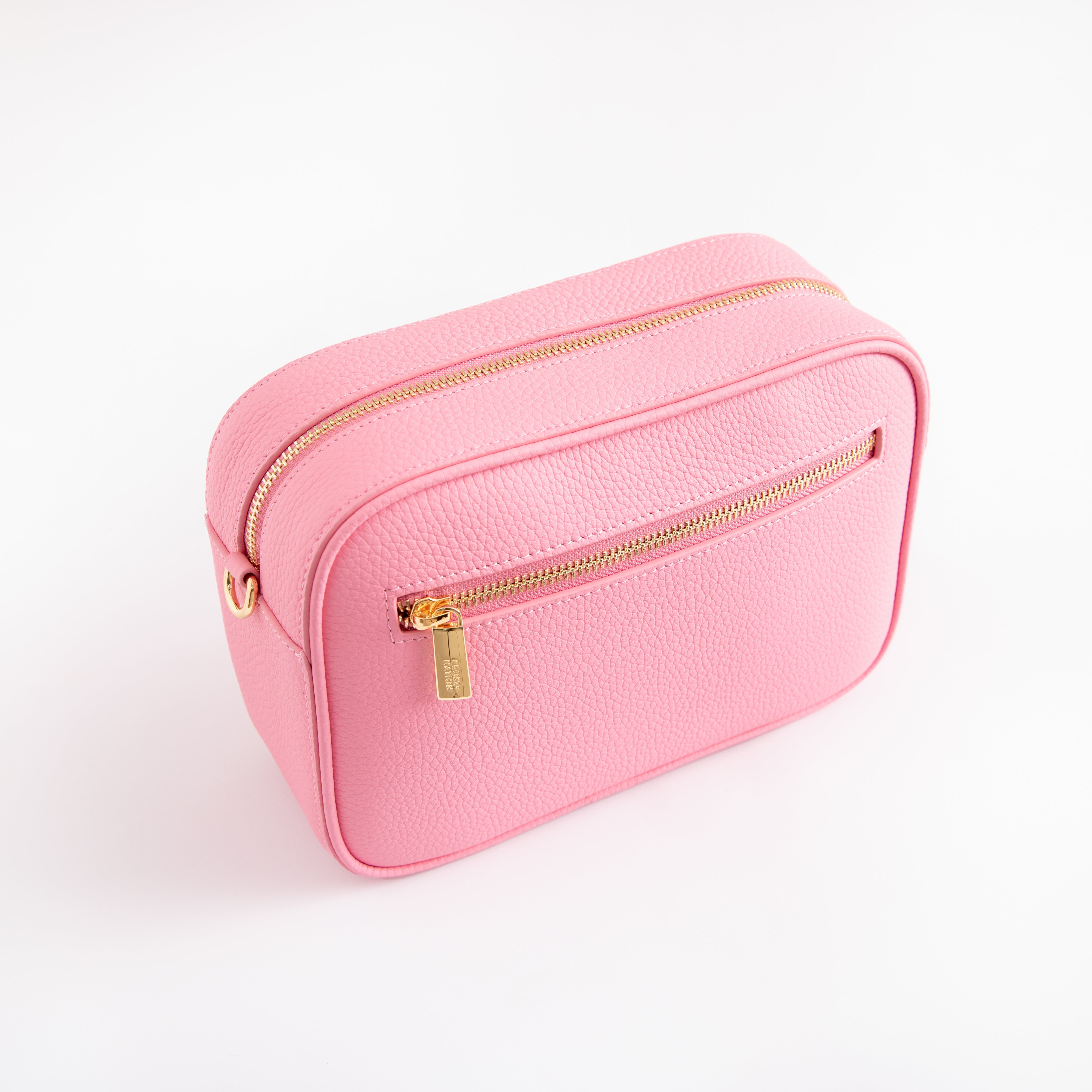 Pink rectangular handbag with gold zipper on a light pink background
