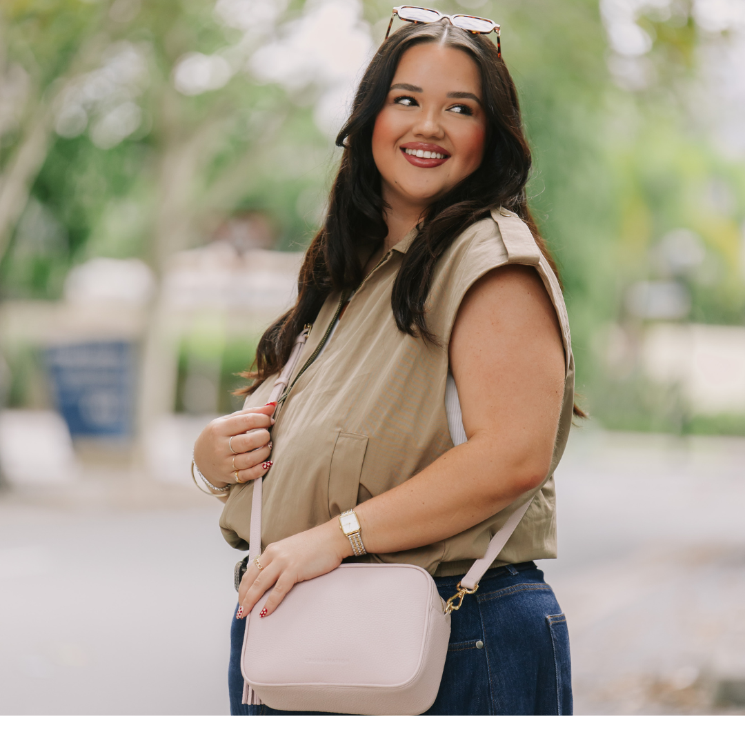 Woman holding a pink handbag outdoors with blurred background