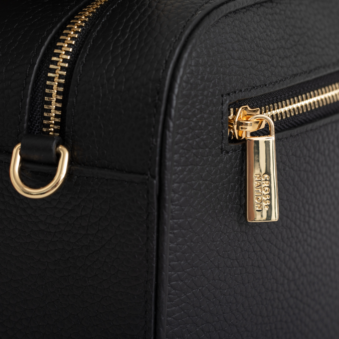 Black leather bag with gold zipper and clasp, featuring the brand Cross Nation