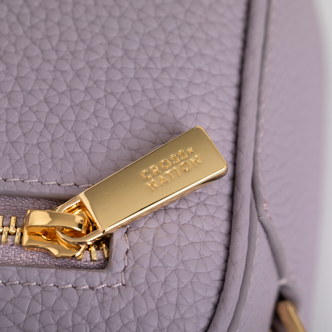 Close-up of a gold zipper pull on a purple leather bag with 'Cross Nation' branding.