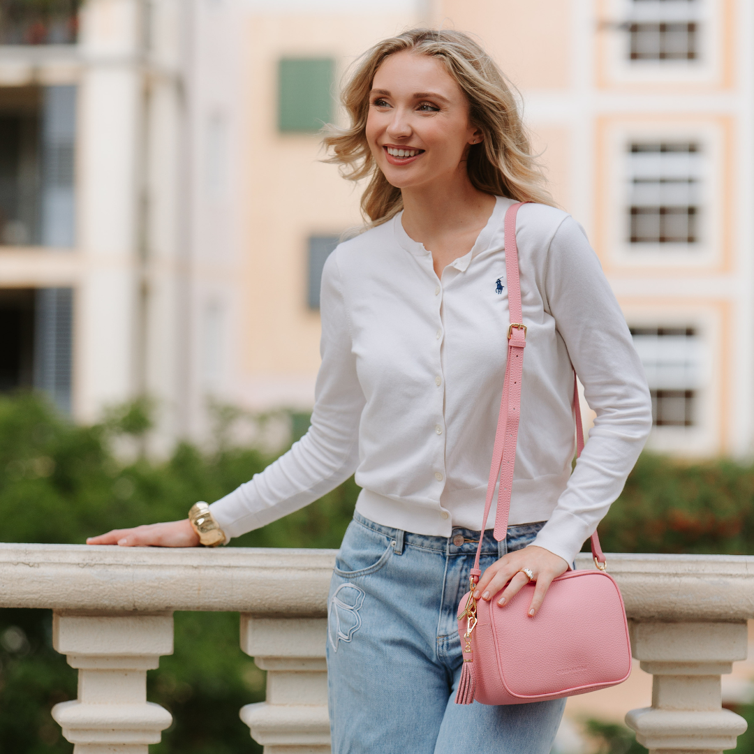 Woman holding a pink handbag in an urban setting