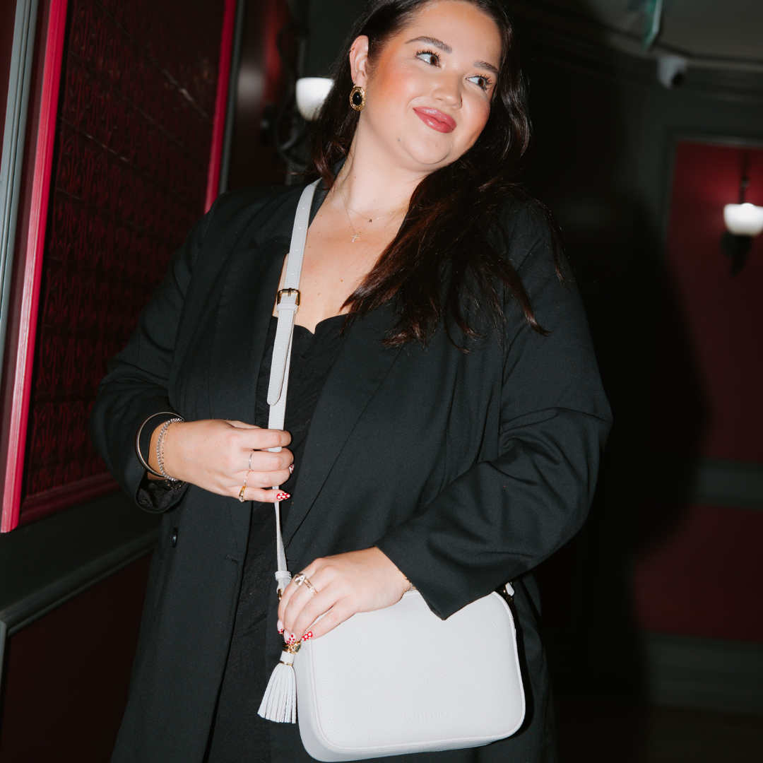 Woman holding a white handbag in an indoor setting