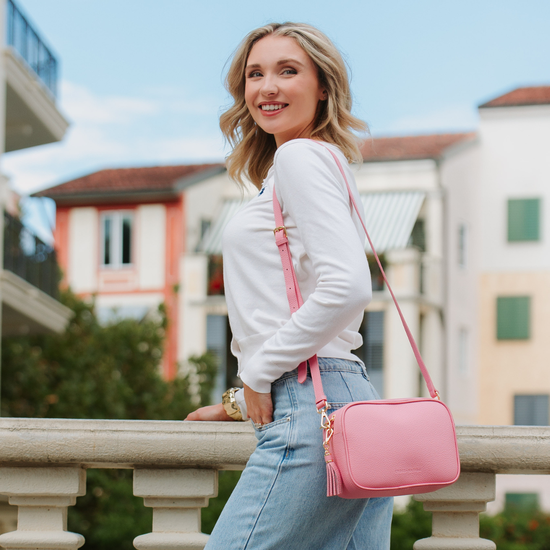 Woman with a pink bag standing outdoors with buildings in the background
