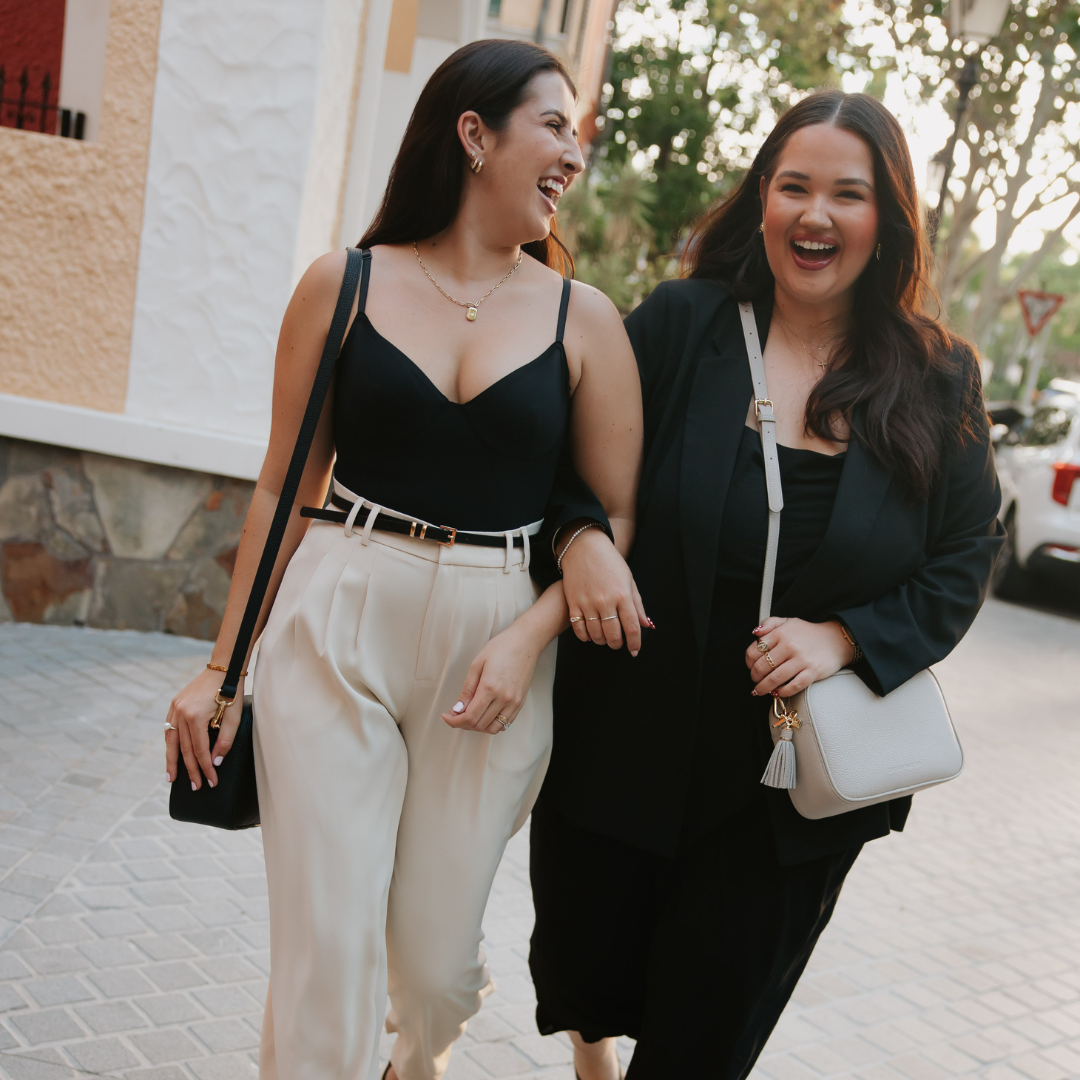 Two women walking together on a street, smiling and laughing.